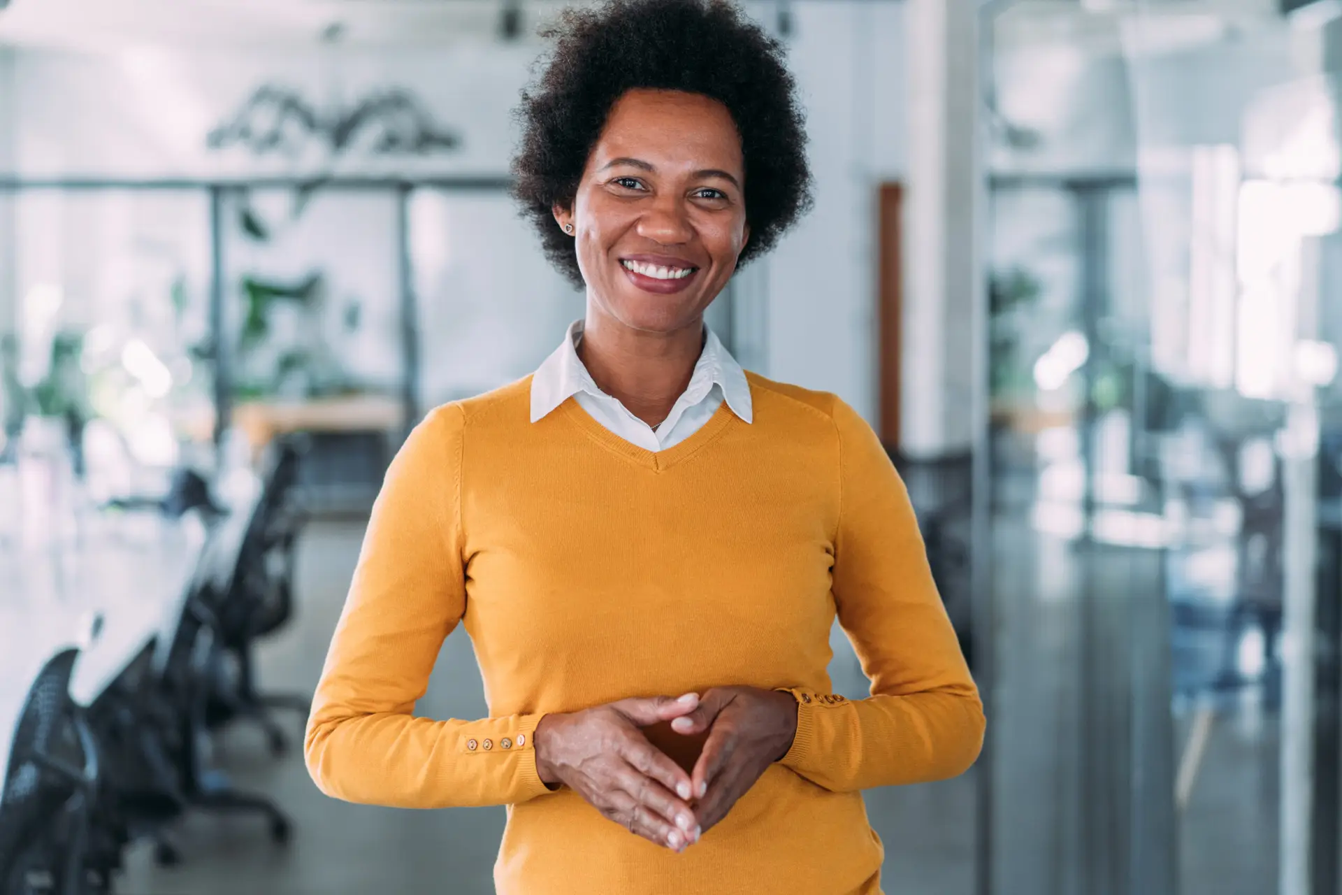 Female executive standing confidently in a modern glass office.