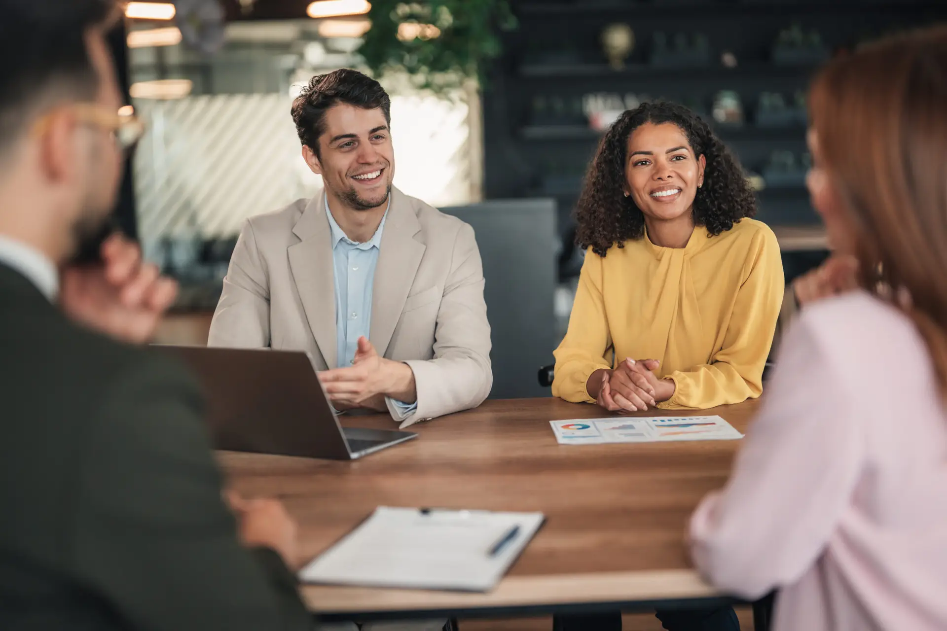 Internal L&D coach and HR manager facilitating a team discussion around a table in a modern office.