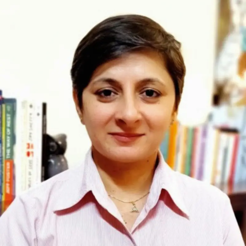 Dr. Madhulika Tyagi, Social Impact Lead and Learning Facilitator at Coacharya Foundation, in a pink shirt in front of a bookshelf