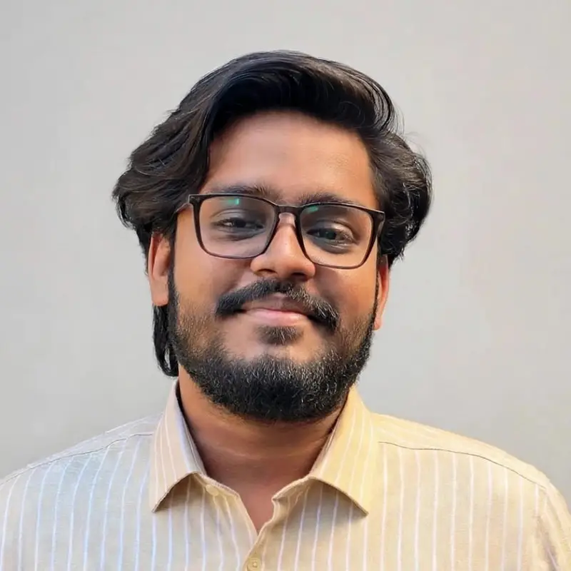 Sinjan Paul, Coacharya team member, smiling in a striped cream shirt