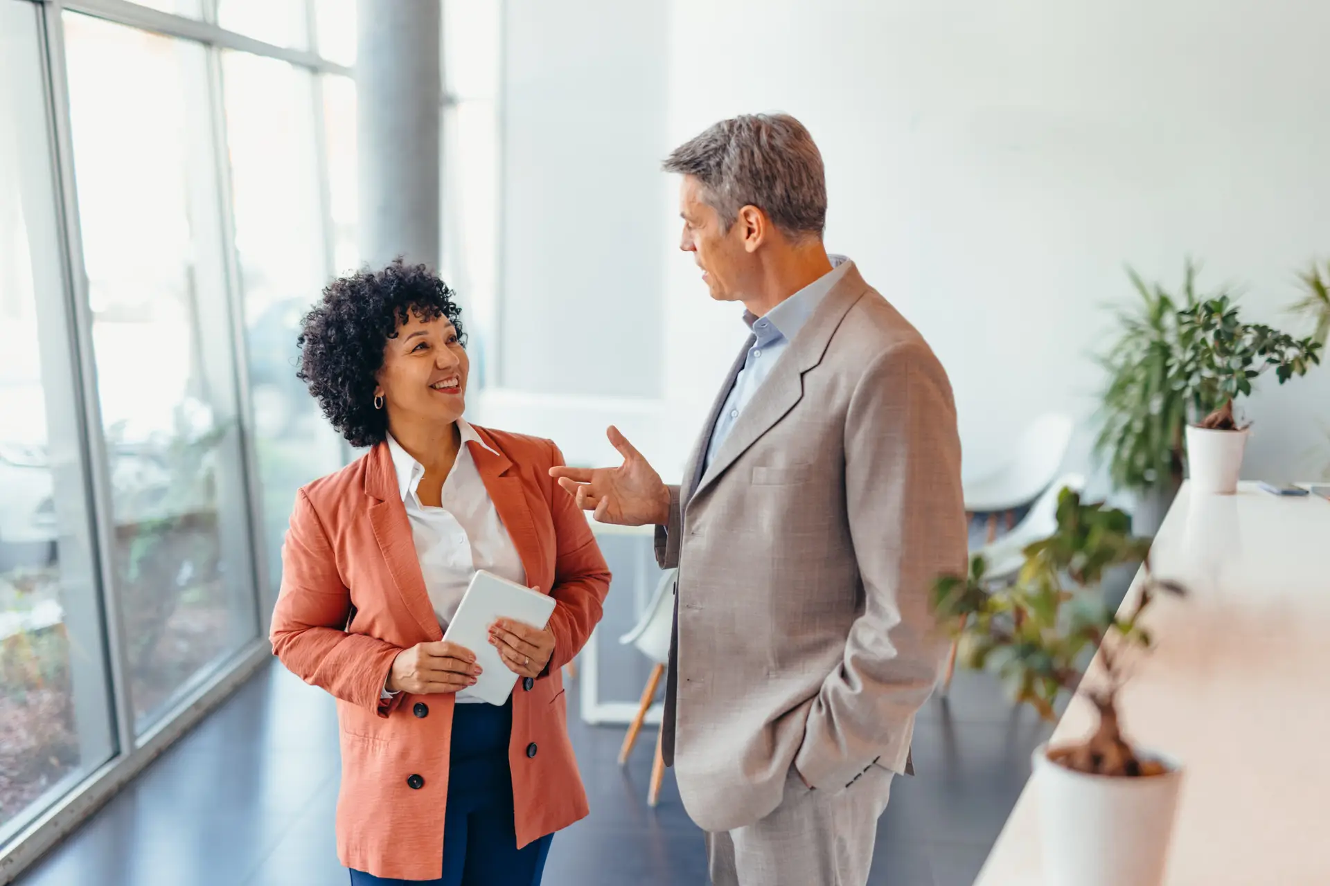 Client and coach in a modern office setting are engaged in a focused discussion. Both express professionalism and collaboration, highlighting teamwork and effective communication in a corporate environment.